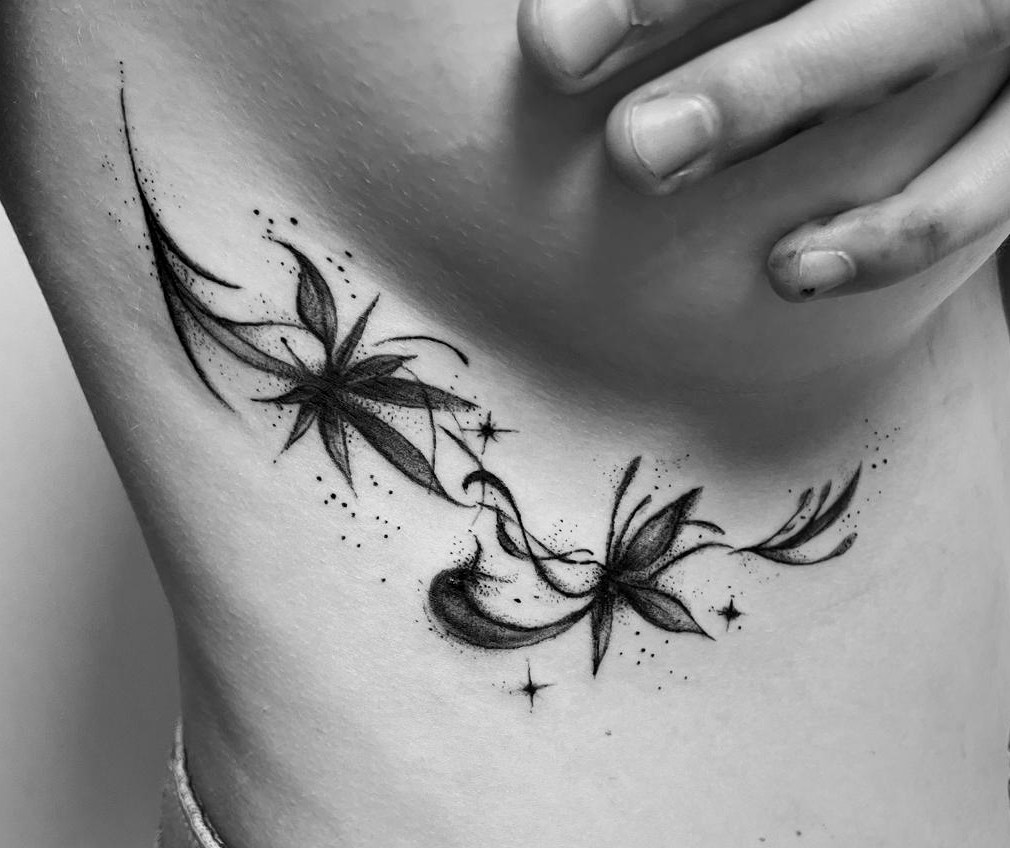 Zwei fein schattierte Blüten mit geschwungenen Linien und kleinen Sternen als Tattoo am Rippenbogen.